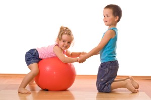 Little firl and boy playing with a large ball on the floor